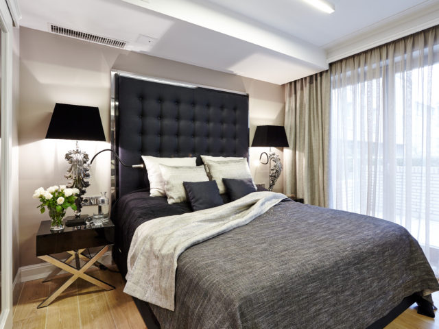 Sypialnia z łóżkiem kontynentalnym i stylizowanymi lampami nocnymi.