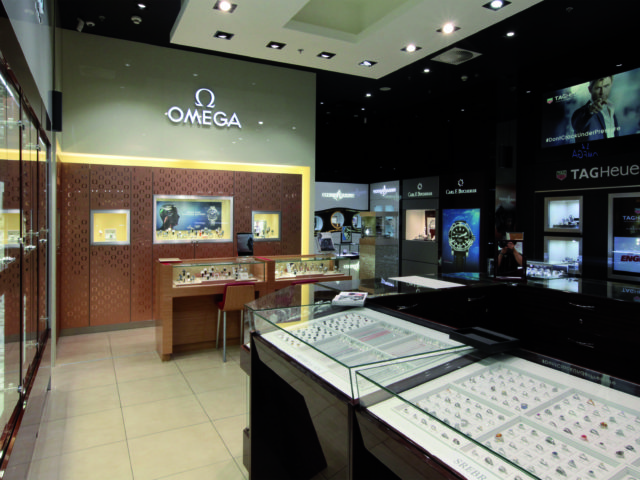 Wnętrze sklepu jubilerskiego. Oszkole wystawy z zegarkami i pierścionkami. Firmy "Omega", "Tagheuer" i "Carl F. Bucherer".