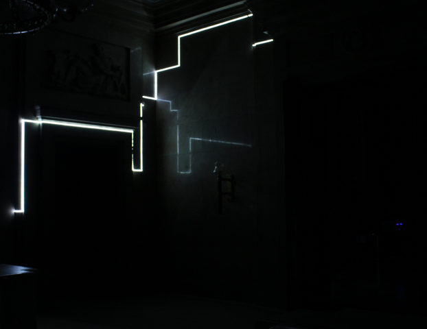 Ciemne pomieszczenie delikatnie oświetlone neonem w kształcie nieregularnej lini. 