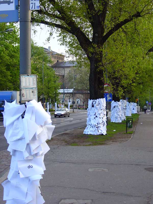 Drzewa obklejone kartkami papieru wzdłuż Alei Niepodległości z perspektywy Zamku Cesarskiego w Poznaniu.