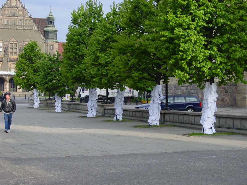 Drzewa obklejone kartkami papieru przed Zamkiem Cesarskim w Poznaniu z widokiem na Uniwersytet imienia Adama Mickiewicza w Poznaniu.