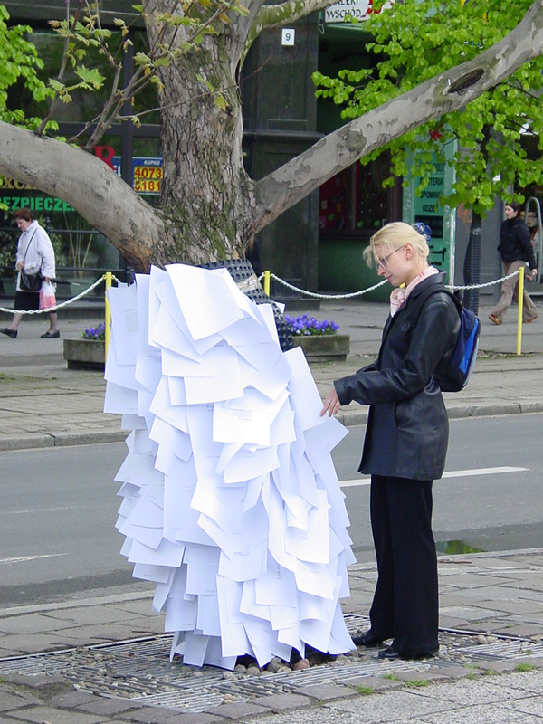 Kobieta przyglądająca się kartkom przymocowanym do drzewa na ulicy 27 Grudnia w Poznaniu.