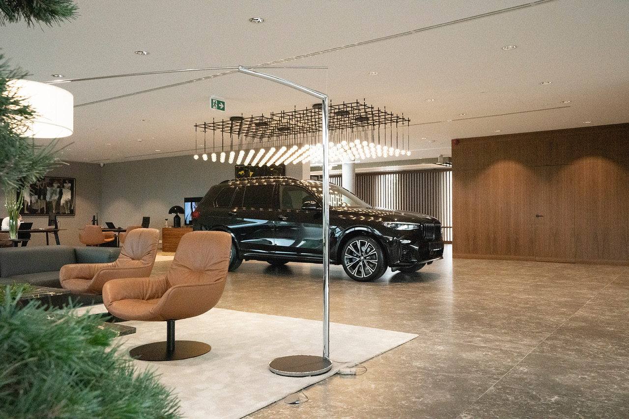 Wnętrze salonu samochodowego BMW; skórzane fotele na dywanie, kanapa, auto, rośliny.